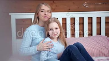 有爱心的年轻妈妈抱着小女儿摆姿势看镜头的画像
